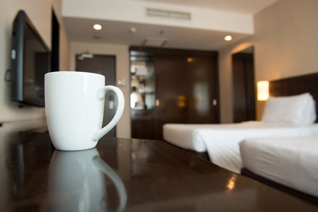 Hotellrum med vit kaffekopp och sängar.