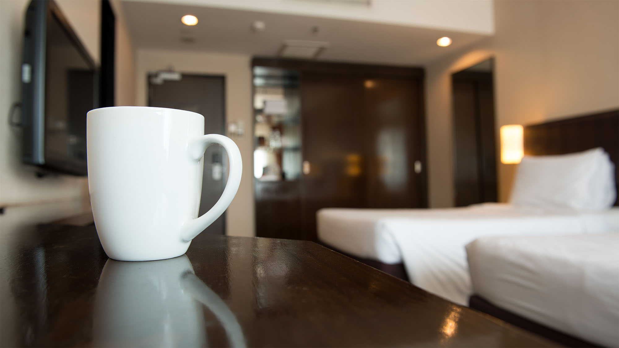 Hotellrum med vit kaffekopp och sängar.
